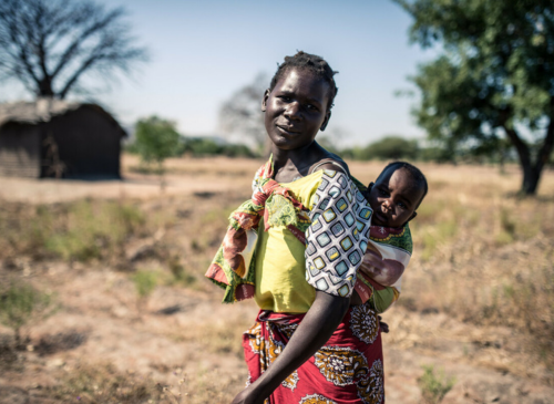 Malawi: Elube (32) stands with her baby in her small plot of farm land. Photo: Aurelie Marrier d'Unienville/Oxfam AUS