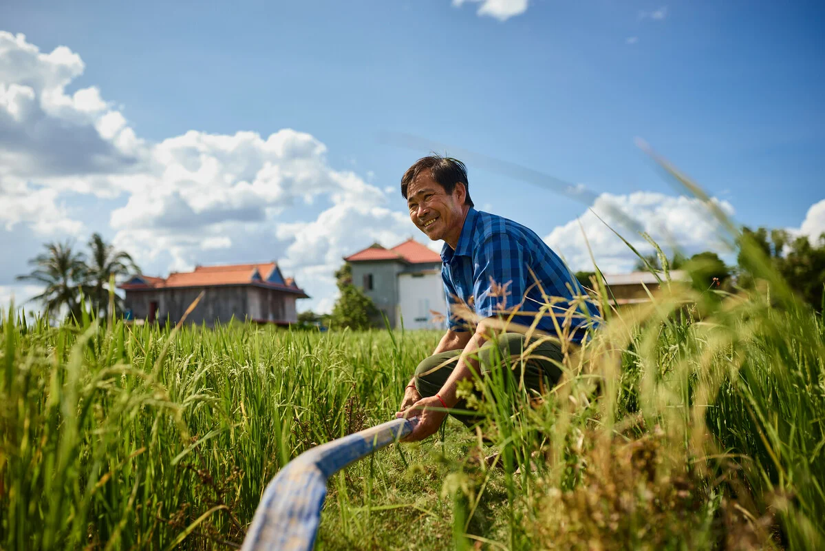 Cambodia: Chana with his rice irrigation system. Chana (pictured) and his wife Sare, both 50s, are part of an Aquaponics pilot project in their village. The pilot gives local villagers the opportunity to grow vegetables in a climate resilient way that can then be used to support their household expenses. Oxfam acknowledges the support of the Australian Government through the Australian NGO Cooperation Program (ANCP). Photo: Patrick Moran/Oxfam