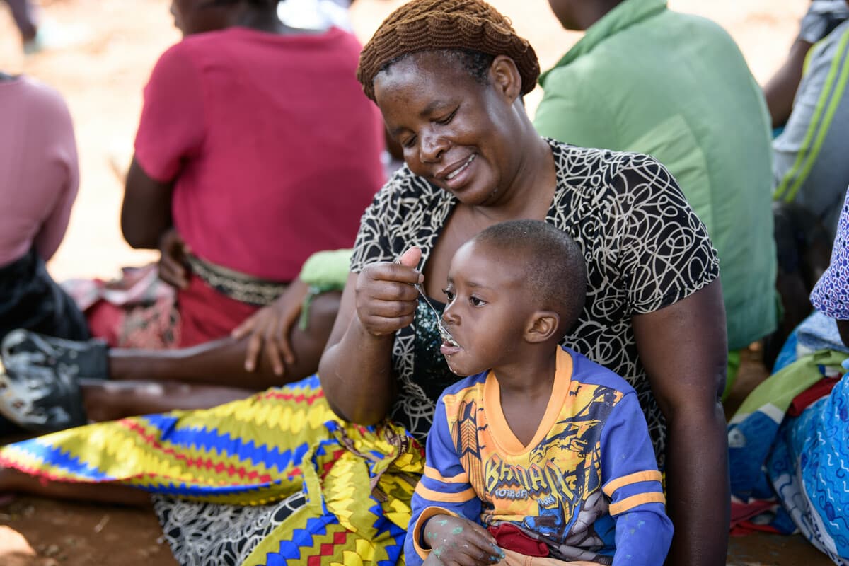 Malawi: Manesi, feeding 5-year-old Chimwemwe* porridge at a displacement camp in Blantyre southern Malawi on Saturday 25 March 2023. Thoko Chikondi / Oxfam