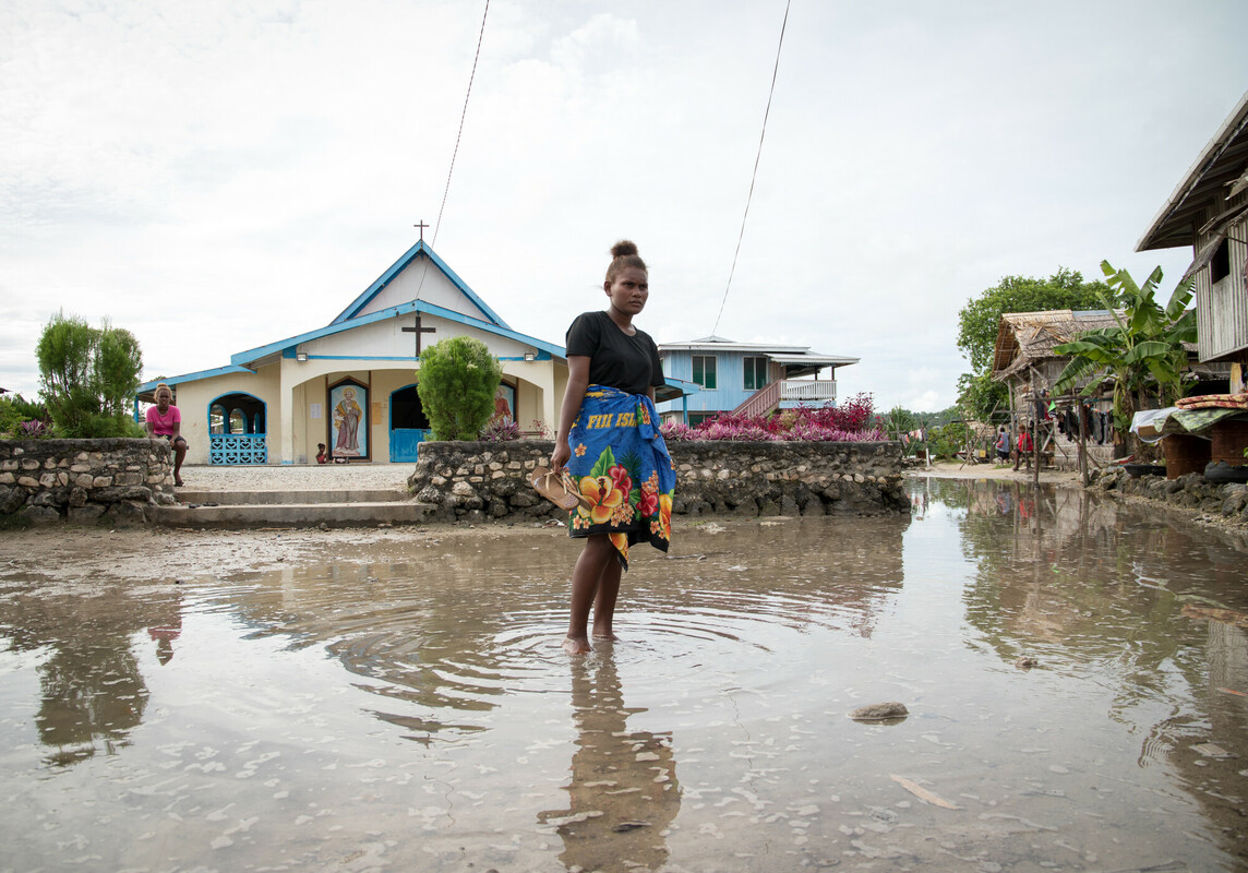 Lilisiana, Malaita Province, Solomon Islands: Grace Namoi (19), a student at the local high school, walks through water left in the town square after a high tide. Grace worries about the future of her town with the visible impacts of a changing climate.