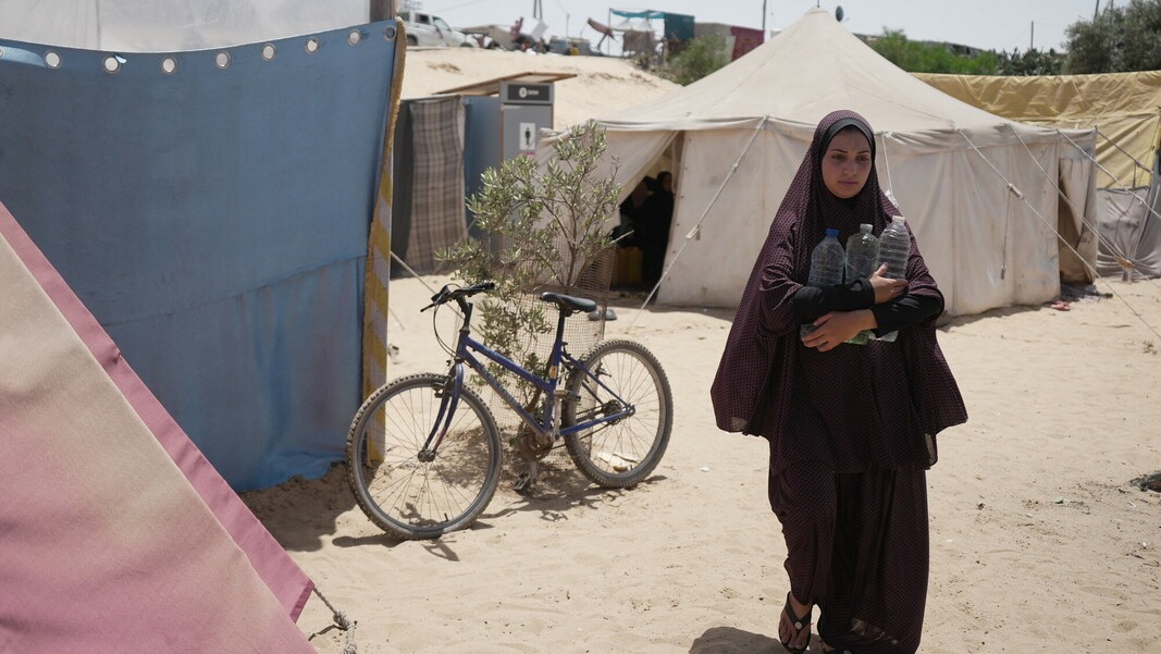 Palestinian Territory, Occupied: Duaa Abu Sabha holds water bottles while walking to her tent in the Al-Mawasi area in Khan Yunis Governorate. Photo: Alef Multimedia/Oxfam.