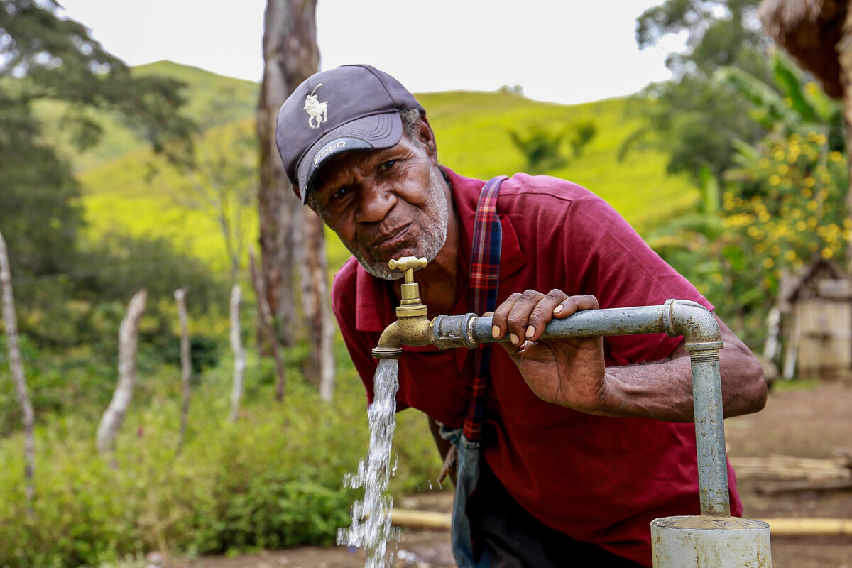 Papua New Guinea: Esoi of Nogorunte community in Papua New Guinea (PNG), drinks water from a newly built tap outside his home. Photo: Jeshua Hope / Oxfam